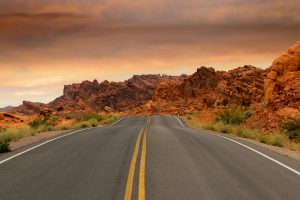 Picture of a two lane road with a surrounding rock formation. Photo courtesy of Pixabay via Pexels.com.